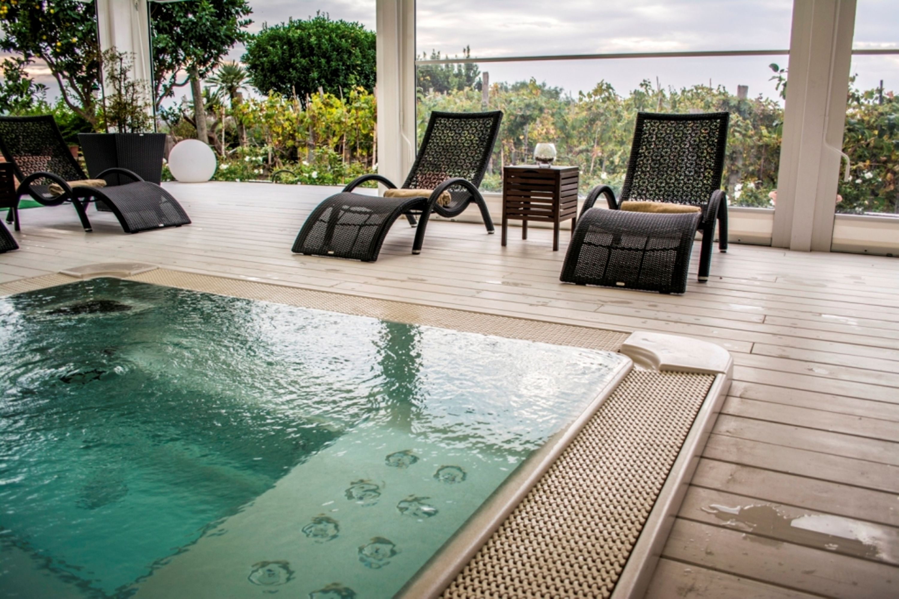 Una piscina interior con sillones de descanso y una pequeña mesa.