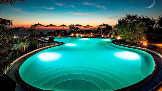 A swimming pool with a crescent moon in the sky, surrounded by palm trees and lounge chairs. - Tenuta del Poggio Antico (Forio)