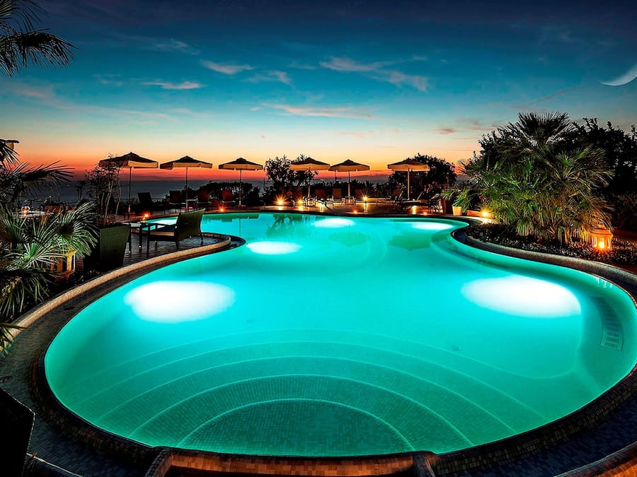 Una piscina al aire libre, sombrillas, sillones reclinables de piscina