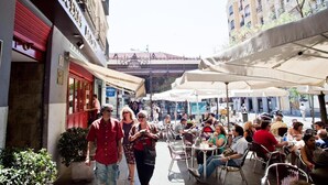 An outdoor café with tables and chairs, surrounded by buildings and a pedestrian walkway. - Hostal Abaaly (Madrid)