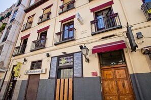 A multi-story building with a restaurant on the ground floor, featuring a wooden door and a sign that reads "La Forja Restaurant." - Hostal Abaaly (Madrid)