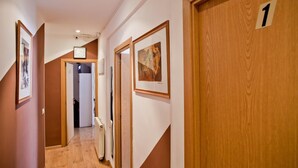 A hallway with wooden doors, numbered 1, and framed artwork on the walls. - Hostal Abaaly (Madrid)