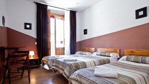 A hotel room with two beds, a wooden desk, a chair, and a window with curtains. - Hostal Abaaly (Madrid)
