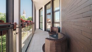 A balcony with wicker furniture, large windows, and a view of a tower. - Hotel Milano Navigli (Milan)