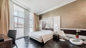 A modern hotel room with a large bed, a desk, a chair, a bedside table, a modern toilet, and a large window with curtains. - Hotel Milano Navigli (Milan)