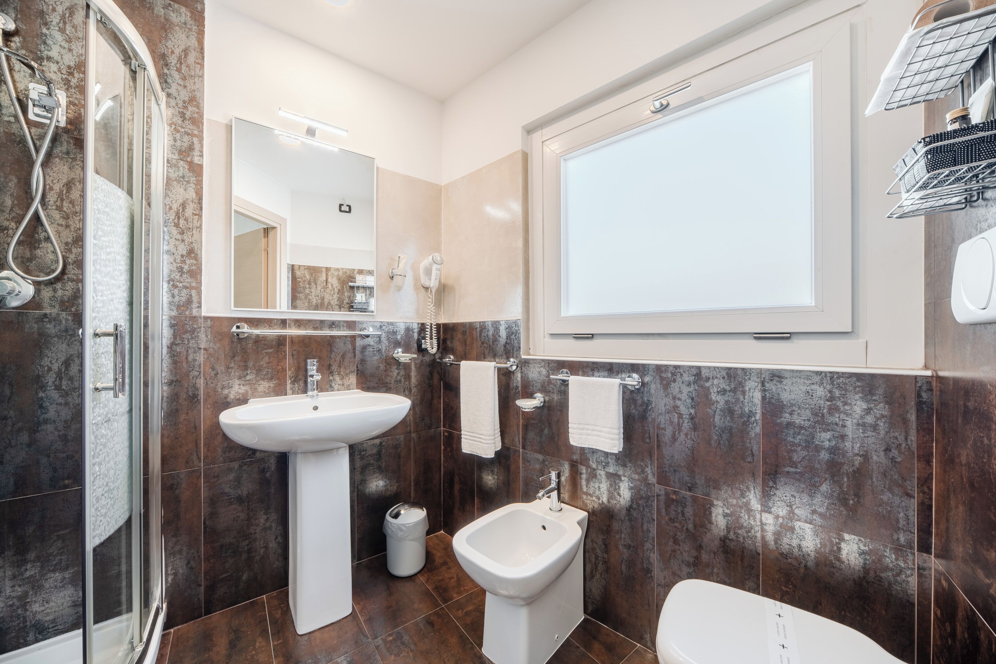 Ein modernes Badezimmer mit Duschkabine, Standwaschbecken, Bidet und großem Spiegel.