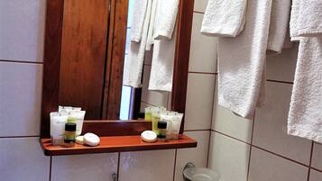 A bathroom with a white sink, a wooden-framed mirror, and a towel rack with white towels.
