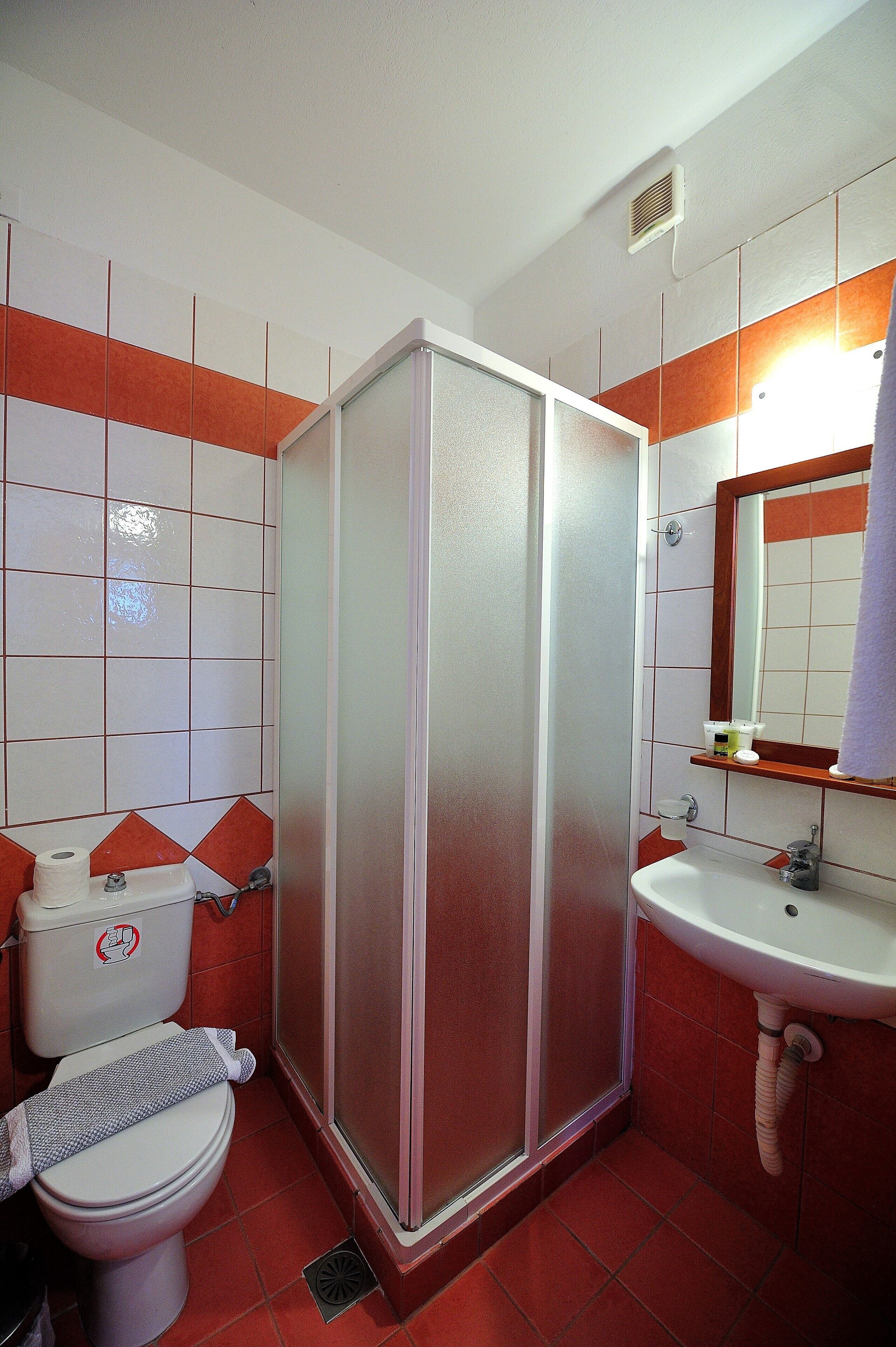 A bathroom with a toilet, sink, and shower stall.