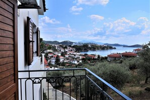 Uma varanda com vista para uma cidade costeira, incluindo casas com telhados vermelhos e um corpo de água.