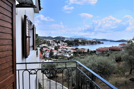 A balcony with a view of a coastal town, including houses with red roofs and a body of water.