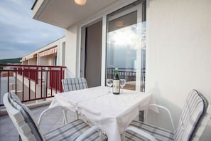 Un balcon avec une table dressée pour deux personnes, deux chaises et une bouteille de vin.