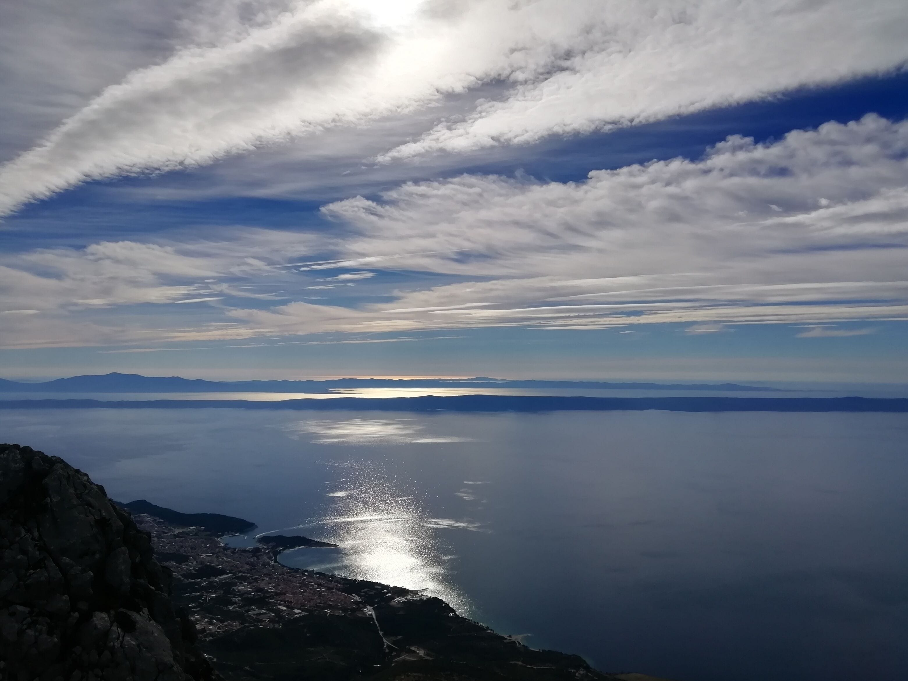 A coastal landscape with a view of the sea and distant mountains.