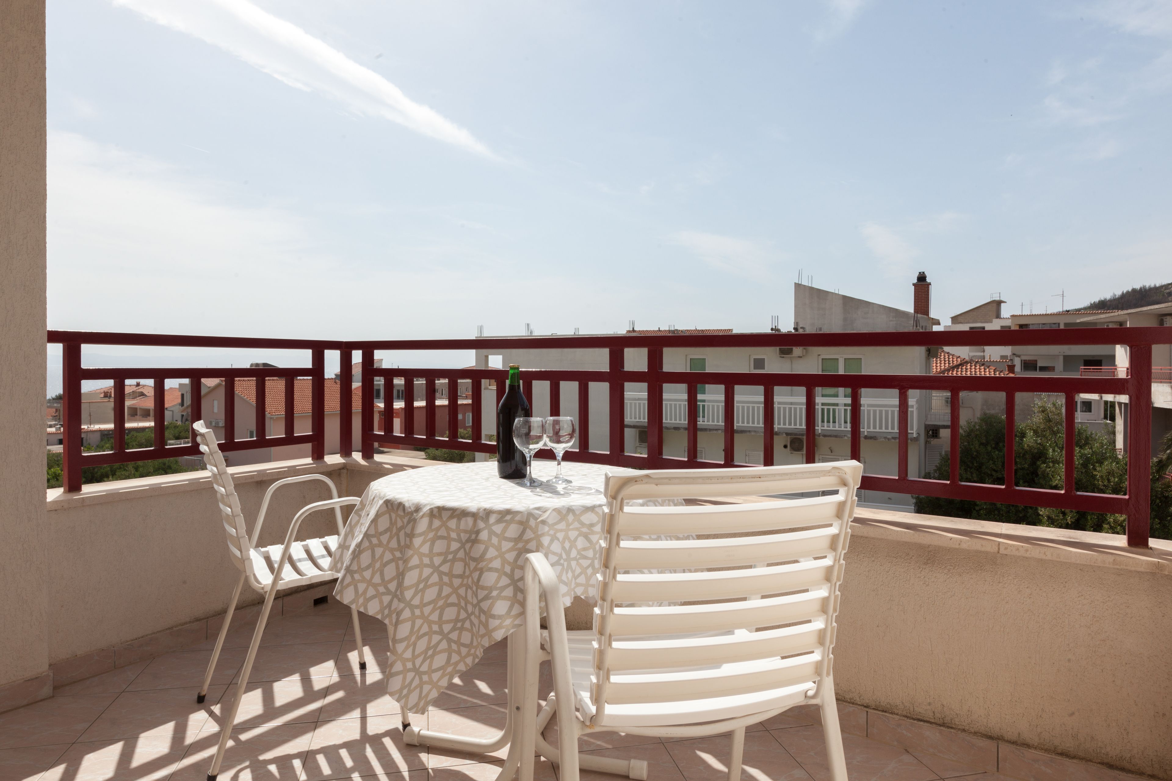 En balkon med et bord, stole, en flaske og to glas.