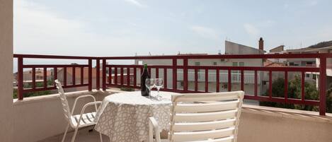 En balkon med et bord, stole, en flaske og to glas.