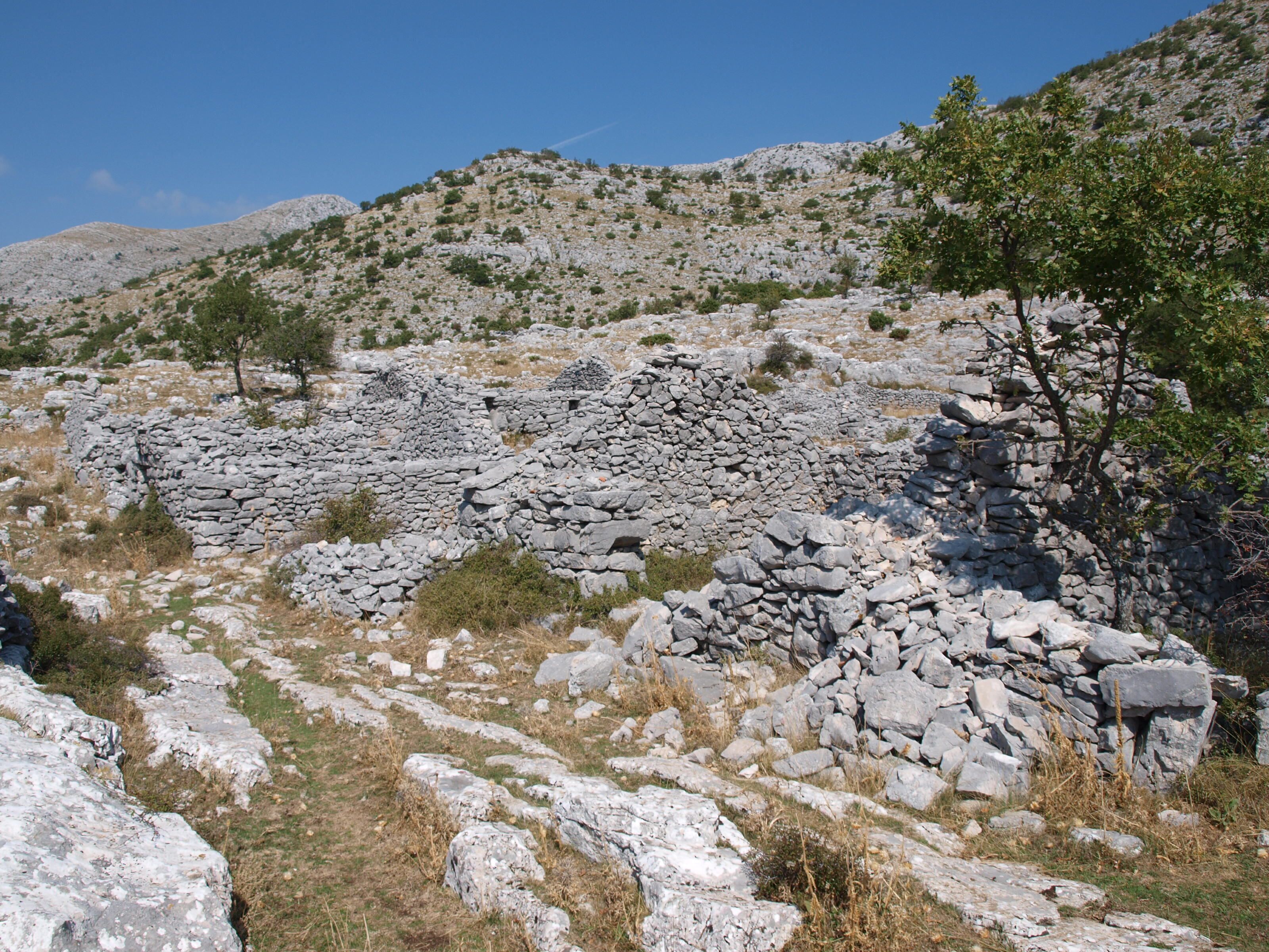 Un paisaje rocoso con muros de piedra y vegetación escasa.