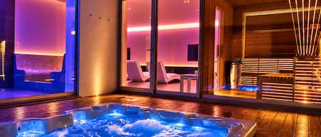 Un área de spa moderna con un jacuzzi, paredes de vidrio y suelo de madera.