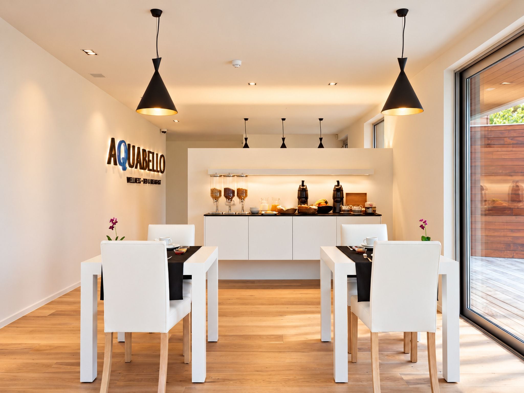 Una zona de menjador moderna amb mobiliari blanc i il·luminació penjant.