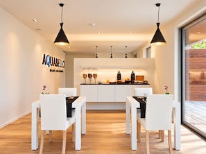 A modern dining area with white furniture and pendant lighting. - Aquabello (Roeselare)