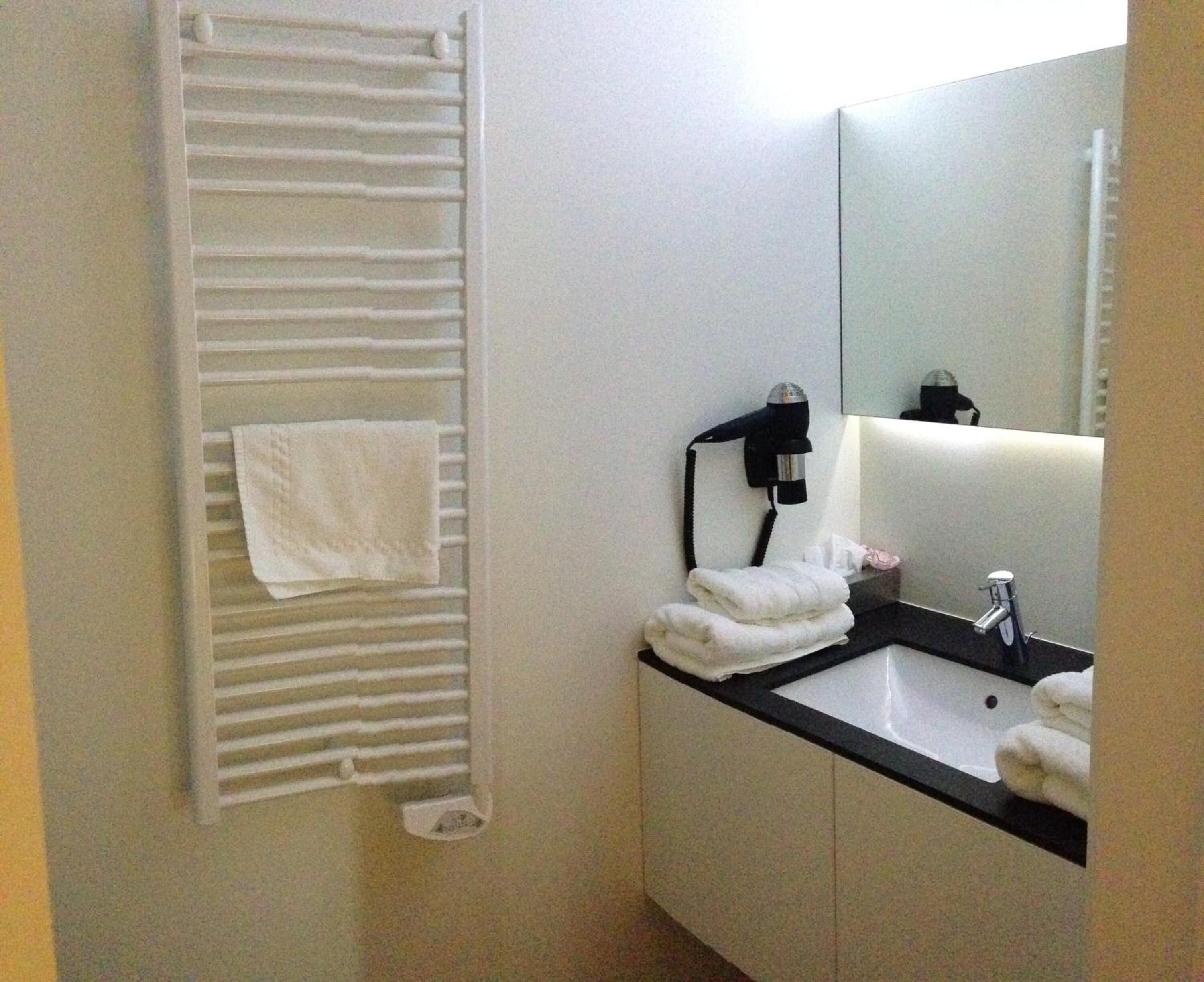A bathroom with a towel rack, a hairdryer, a sink, and a mirror.
