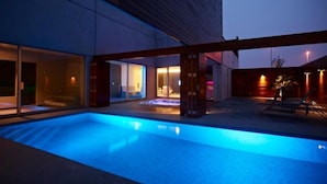A modern outdoor swimming pool area with a hot tub, glass doors, and a wooden deck. - Aquabello (Roeselare)