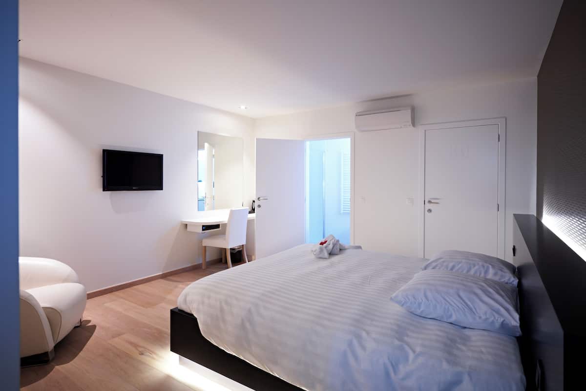 Un dormitorio moderno con cama, escritorio, silla, televisor y armario.