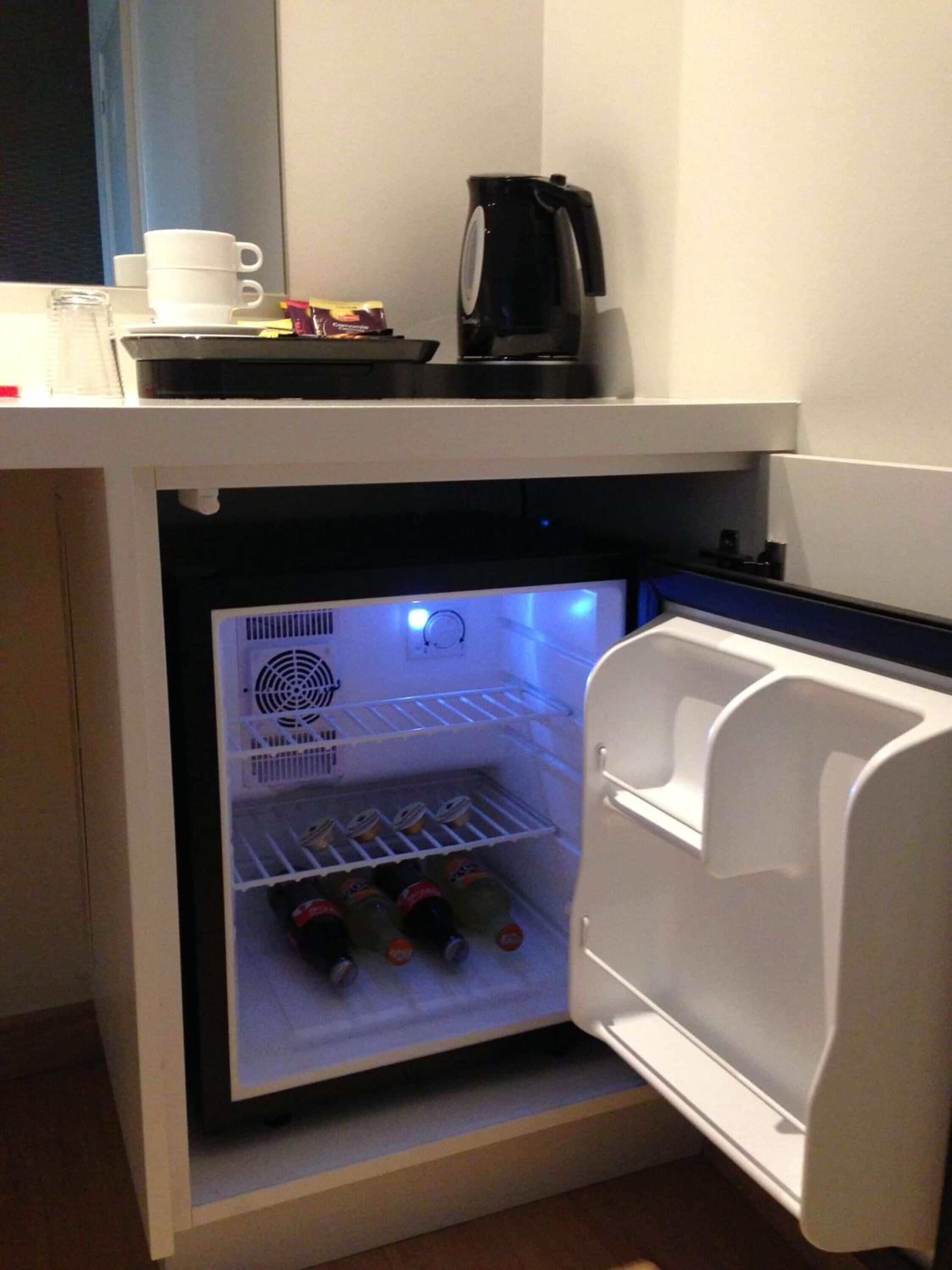 Un refrigerador compacto con una cafetera y una taza encima.