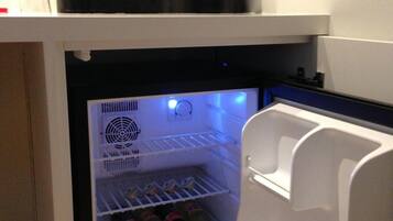 Un refrigerador compacto con una cafetera y una taza encima.