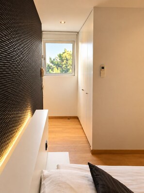 A modern bedroom with a large window, a built-in wall unit, and a bedside table. - Aquabello (Roeselare)