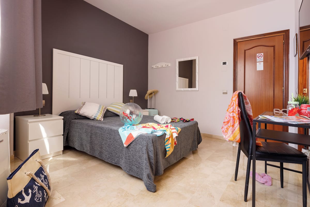 Une chambre à coucher comprenant un lit, une table de chevet, une chaise et un bureau avec une autre chaise.