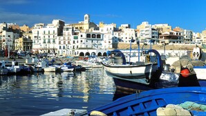 Un port où sont amarrés des bateaux, un ciel bleu dégagé et des bâtiments en arrière-plan.