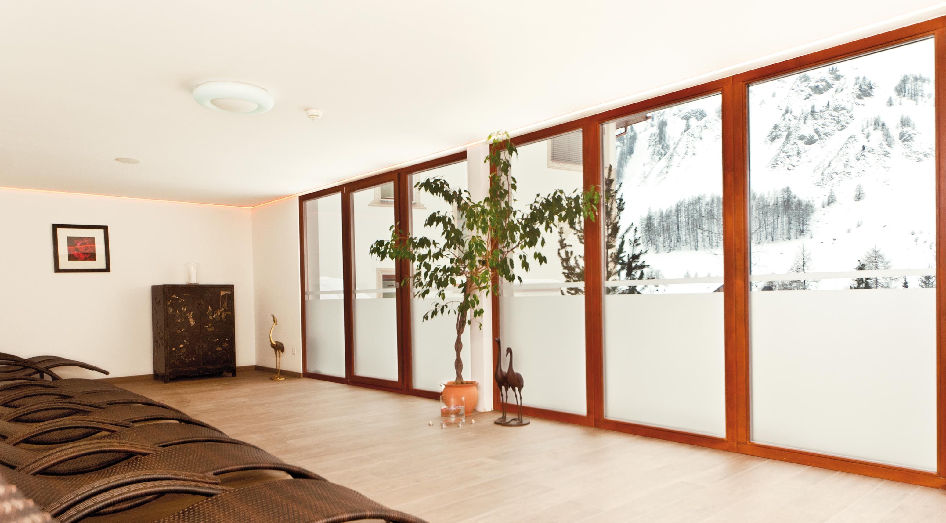 A spacious room with a large sliding glass door leading to a snowy outdoor area, a wooden floor, and a dark wooden cabinet.