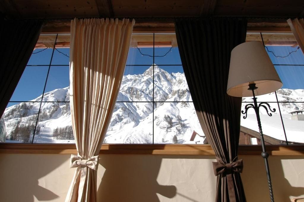 A room with a window overlooking a snow-covered mountain.