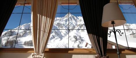 A room with a window overlooking a snow-covered mountain.