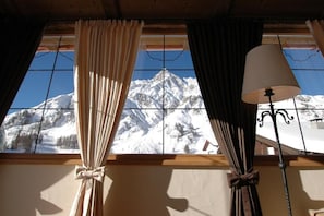 A room with a window overlooking a snow-covered mountain.