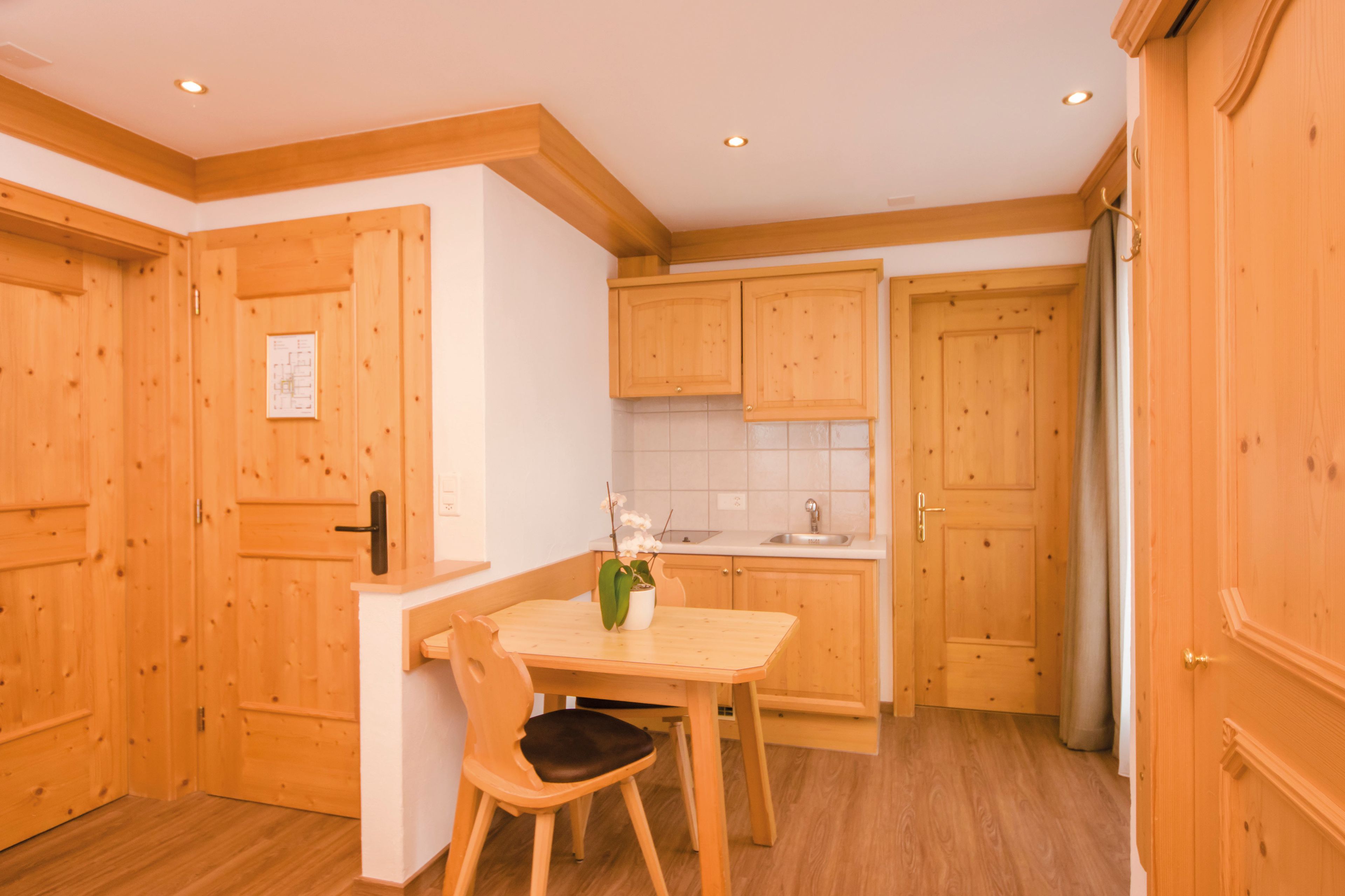 A kitchen with wooden cabinets, a dining table with chairs, and a refrigerator.