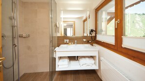 A modern bathroom with a glass shower enclosure, a large mirror, and a built-in sink with a vanity. - Waldpark (Samnaun)
