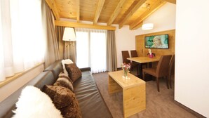 A cozy living room with a sofa, a wooden coffee table, and a dining area with chairs and a table. - Waldpark (Samnaun)