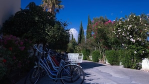 A bicycle parked on a paved path with a white basket attached to the rear. - Manine Apartments (Kos)