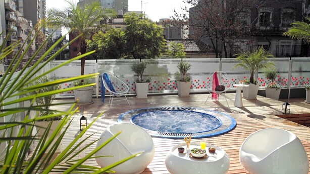 A rooftop pool area with a hot tub, lounge chairs, and potted plants. - BA Sohotel (Buenos Aires)