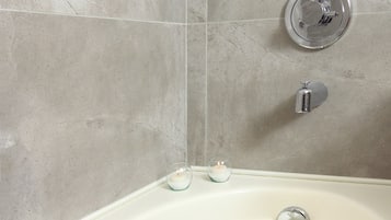 Un bagno con una vasca, un mancorrente e un rubinetto.