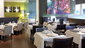 A restaurant with tables set for dining, a large abstract painting on the wall, and a green accent wall. - BA Sohotel (Buenos Aires)