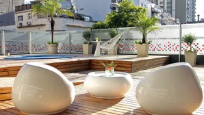 A rooftop terrace with modern seating, potted plants, and a view of surrounding buildings. - BA Sohotel (Buenos Aires)