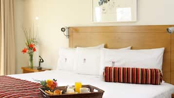 A hotel room with a neatly made bed, a breakfast tray on the bed, and a framed artwork on the wall.