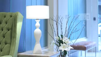 A green tufted chair, a white table lamp, and a vase with white flowers.