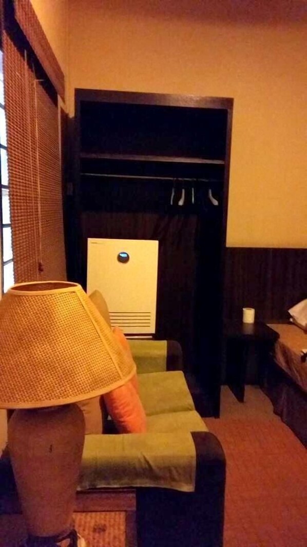 A hotel room with a bed, a small table, a lamp, and a window with blinds. - Cenang Rest House (Langkawi)