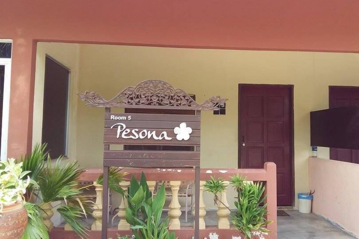 A building entrance with a sign indicating 'Room 5' and 'Pesona'.