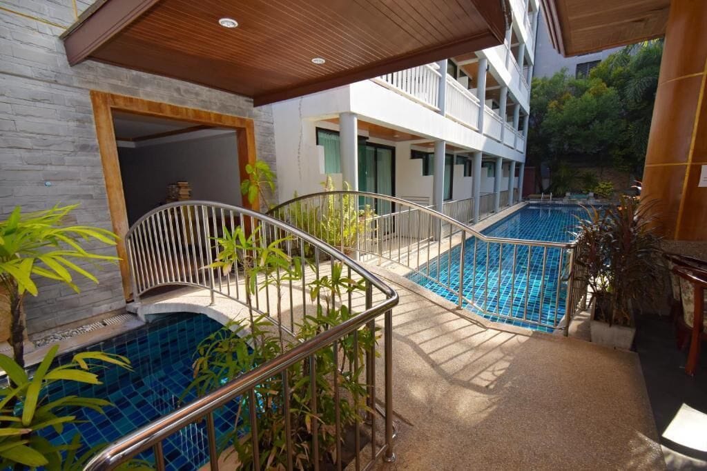 A pool area with two pools, a wooden ceiling, and a building with balconies.