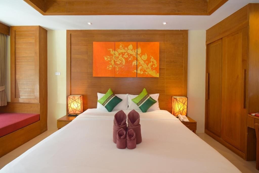 Une chambre d’hôtel avec un grand lit, une tête de lit en bois, deux lampes de chevet et une paire de chaussures posées sur le lit.
