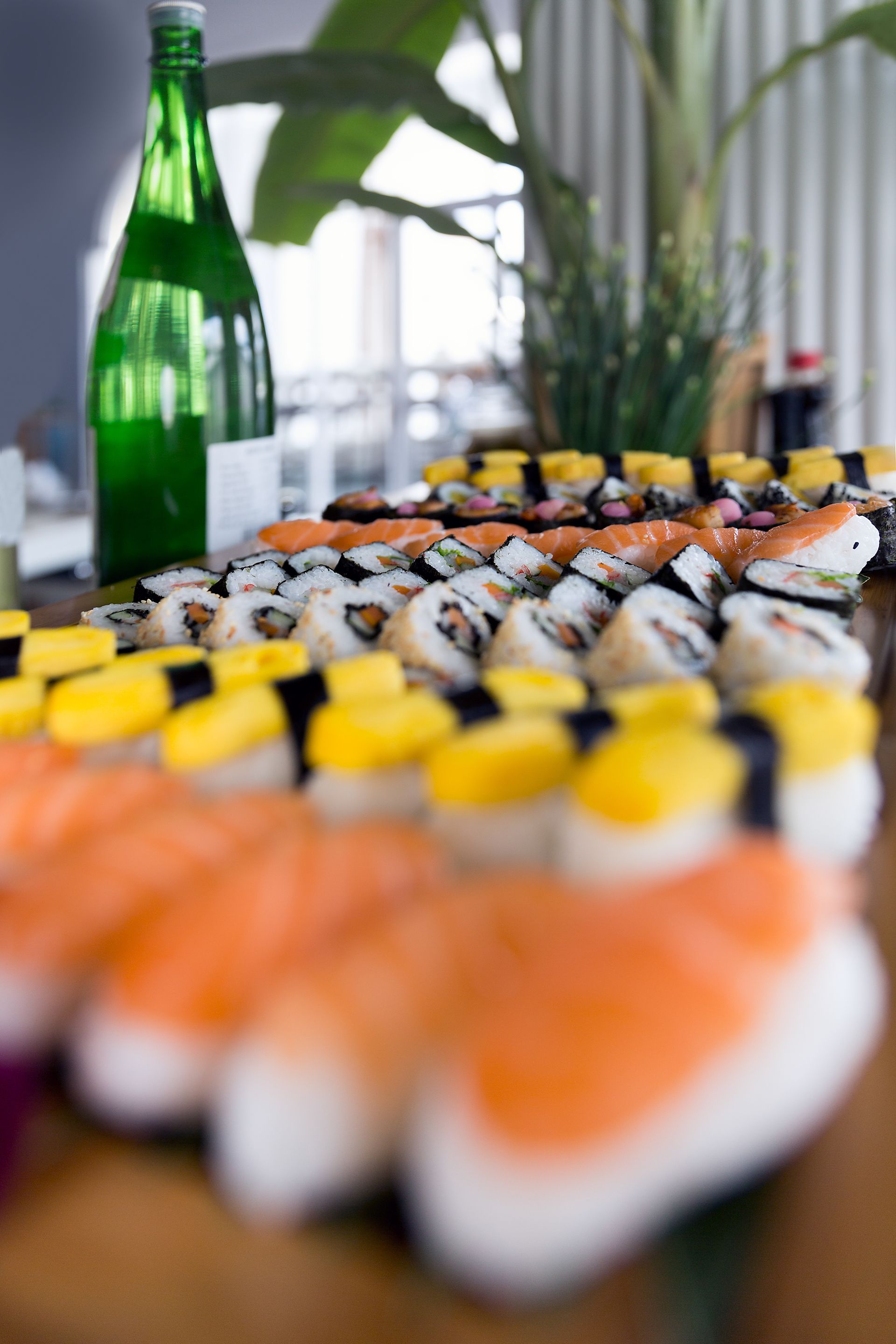 A sushi platter with various types of sushi, including nigiri and maki, arranged on a wooden table.