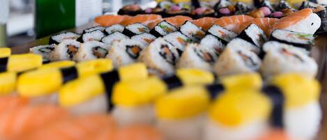 A sushi platter with various types of sushi, including nigiri and maki, arranged on a wooden table.
